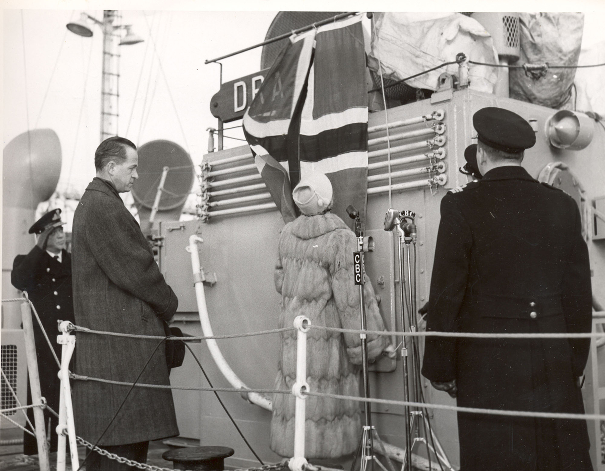 Overtakelsen av River-kl.fregatt KNM "Draug", ex. HMCS Pentang.
Admiral S. Storeheil, , ambassadør A. Gunneng, fru Gunneng som avduker skipes navn, og skipssjef E. Zachariassen.