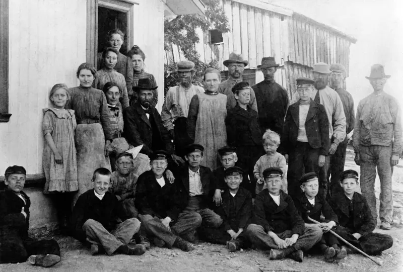 Gruppe med 25 voksne og barn på Stor-Stav, Ringsaker. Stående fra venstre er Karen Røhr, Polla Skaug, Agnete Skaug, Ingrid Røhr, Johan Røhr. På trappa bak kokka er budeia Beate Harstad,ukjent, svensk anleggsarbeider som ble kallt for "NOR", ukjent dame, Magnus Nilsen Staff, ukjent med stripete trøye, August Olsen Branderud, hans sønn Nils Andersen, Kåre Røhr. Foran er 11 gutter fra Toftes Gave, Nedre Sund, Helgøya.