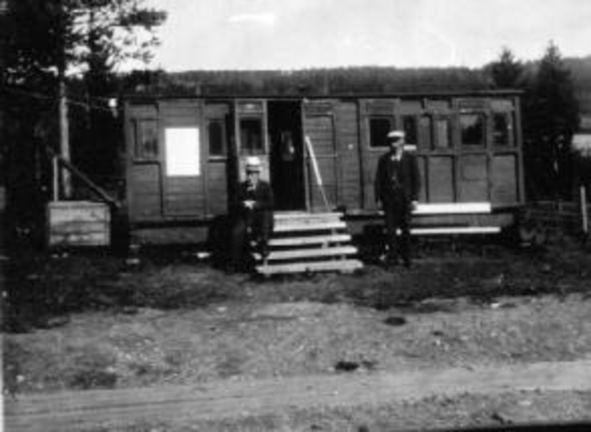 Ringsaker, Rud stoppested anlagt 15.11.1915, Rudshøgda stasjon. En gammel jernbanevogn ble i begynnelsen brukt som stasjonsbygning. Kjøpmann og gårdbruker Jacob A. Rud (1866-1953) var ekspeditør for post og jernbane inntil Christian Nordby ble stasjonsmester i 1918 til 1925, kjøpmann Ole Skaraasen (1856-1922) til høyre,