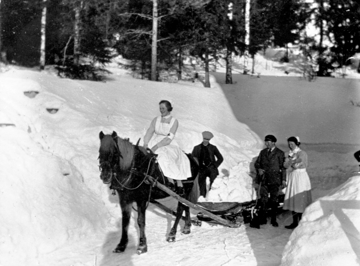 Snørydding ved Ringsaker sykehus ved Moelv med hest og møkkbrett. Røde Kors søster på hesteryggen