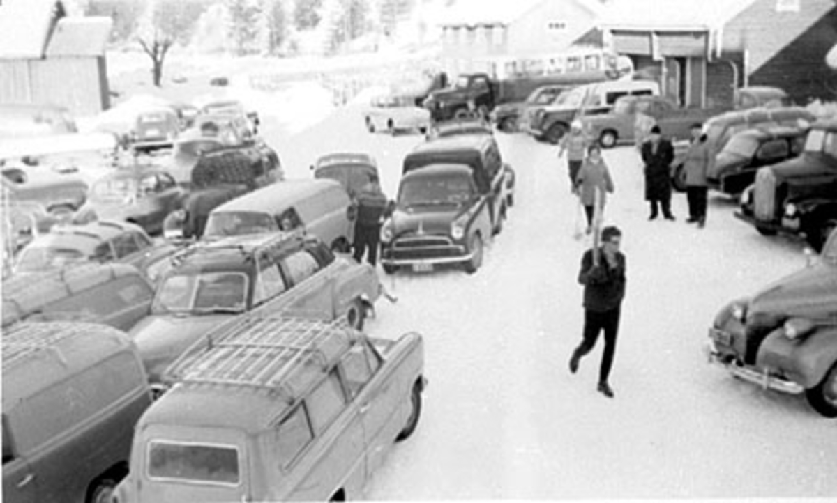 BJØRNSTAD LILLE, PARKERINGSPLASS FOR BILER UNDER SKIHOPPRENN I BJØRNSTADBAKKEN, BILEN TIL HØYRE: BARE FORPARTEN SYNLIG: 1939 CHEVROLET. Nærmest til høyre:Nesen til en Chevrolet 1939. Mørk bil midt i bildet: Morris Oxford varebil ca. 1955. 