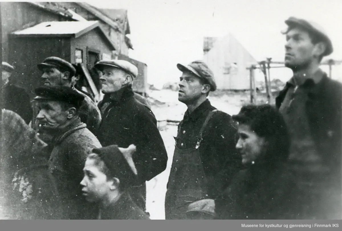 Folk fra Hamningberg får opplest Kongens proklamasjon om samarbeidet med Sovjetunionen. 1944. De to menn til høyre er antatt brødrene Alfred og Johan B. Nilsen, dama mellom dem er antatt Elida Esbensen.