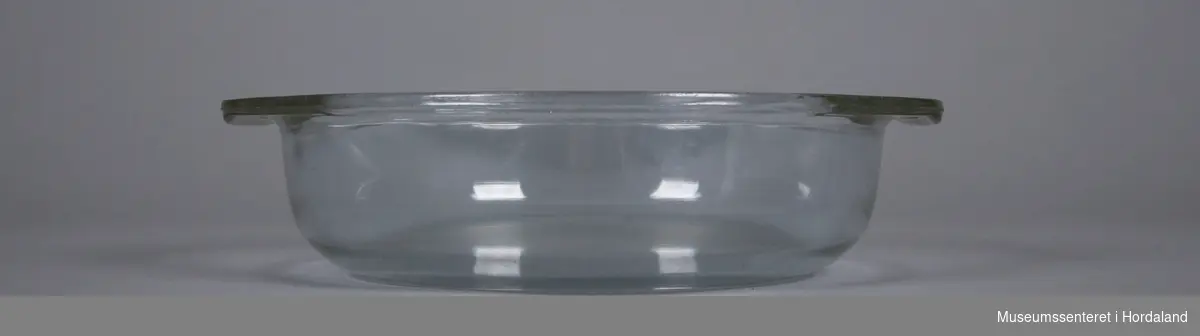 Rund glasskål med handtak som går i ett med skåla oppe. 
