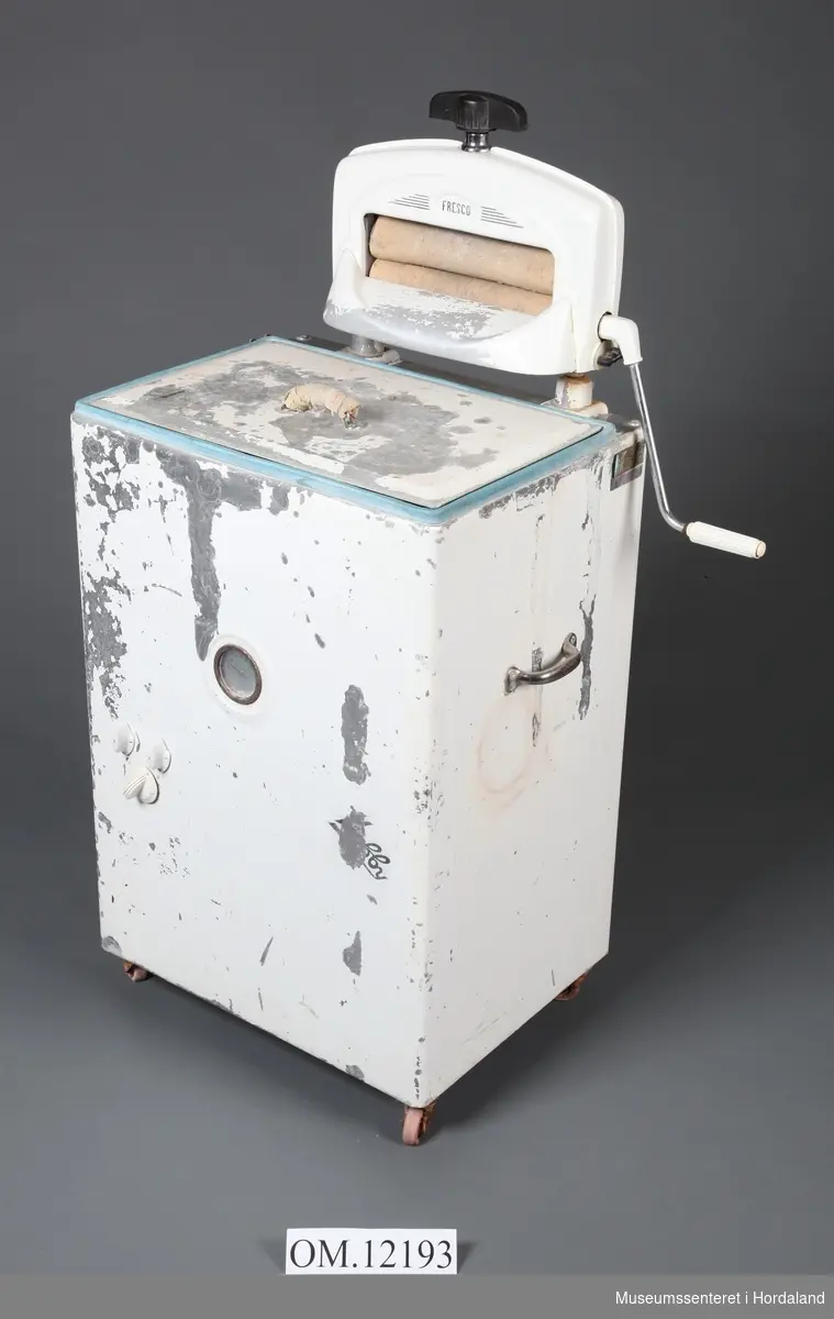 Pulsatormaskin (vaskemaskin) med rulle og lok. Merke: Hobby. Rulle har merke Fresco, og er montert oppå på maskinen. Kvitmåling flassar av. Hobby-merket frampå er nesten vekke. Lok med handtak med surra fille rundt.Produsert 1950-talet?