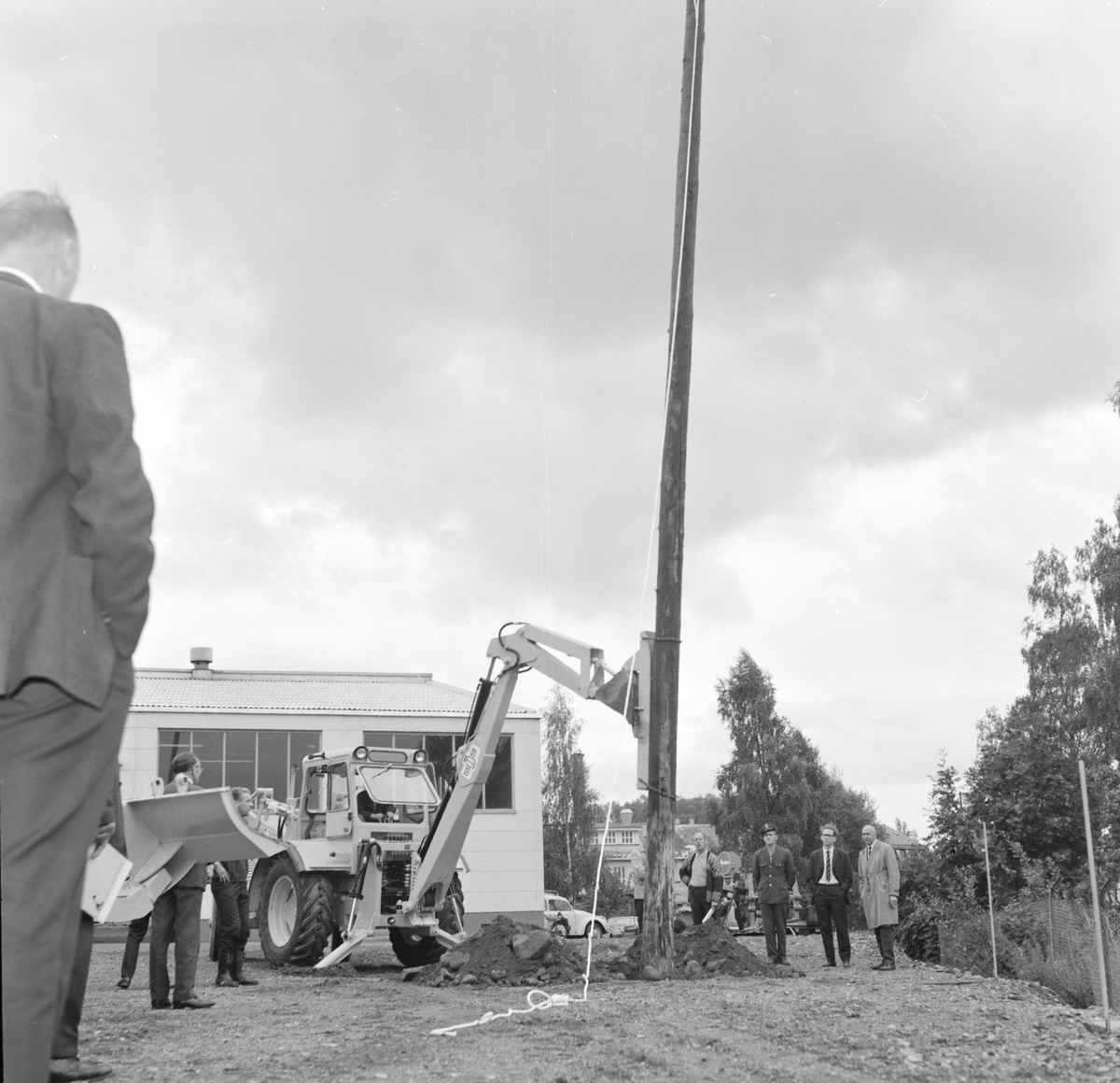 A/S Hymas, Hymas Gravemaskin. (Foto for Telegrafverket?) Demonstrasjon av BM Volvo, traktorgravemaskin. Oppsetting av telefonstolpe. 17. 08. 1967. Brumunddal. Oppsetting av telefonstolpe. 
