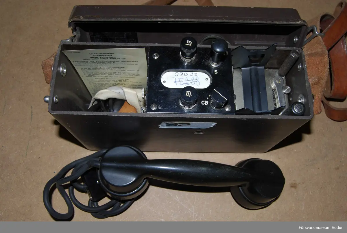 Telefonapparat m/1937 modifierad med klyka på 1950-talet, varvid modellåret ersattes av beteckningen MT (Med Tillbehör). Bruksanvisning medföljer.