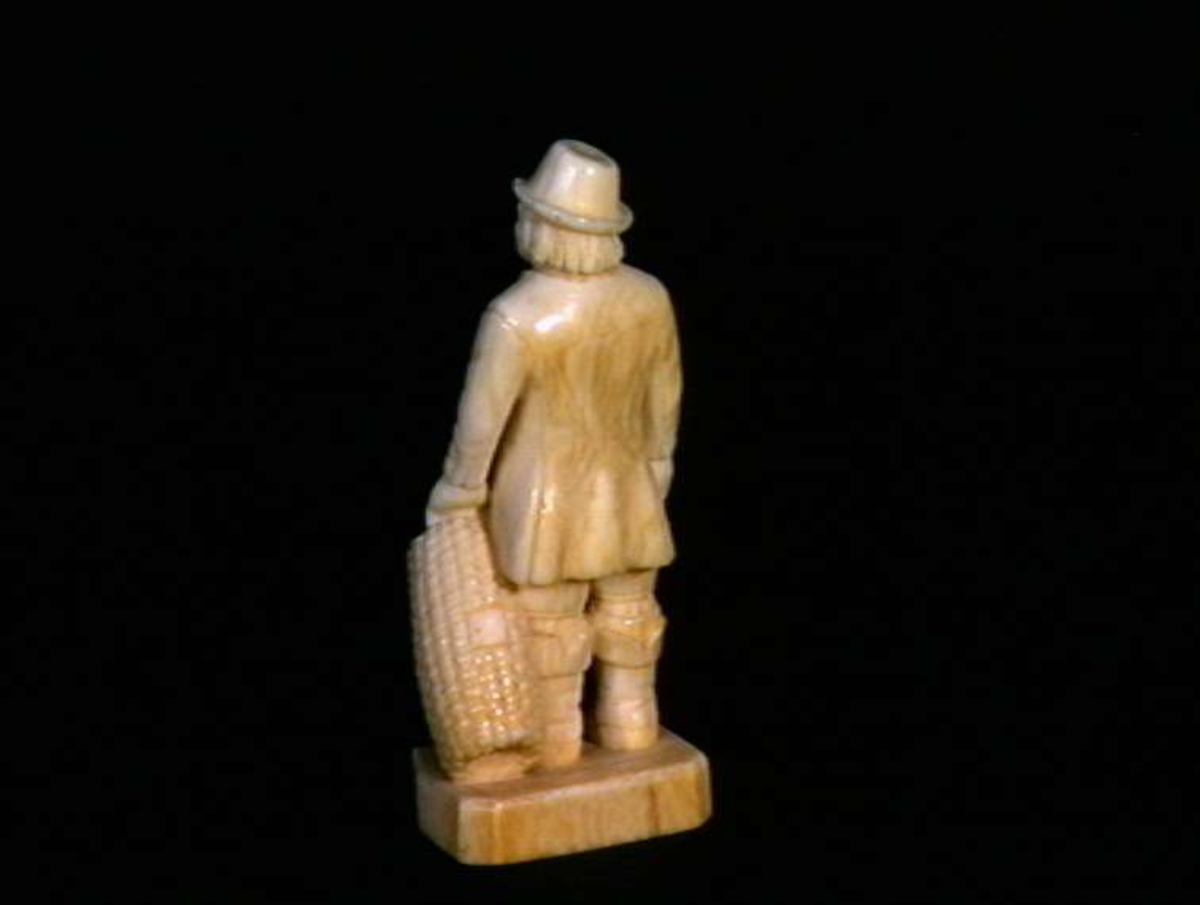 Mannsfigur i elfenben som holder en hummer og en hummertine.
