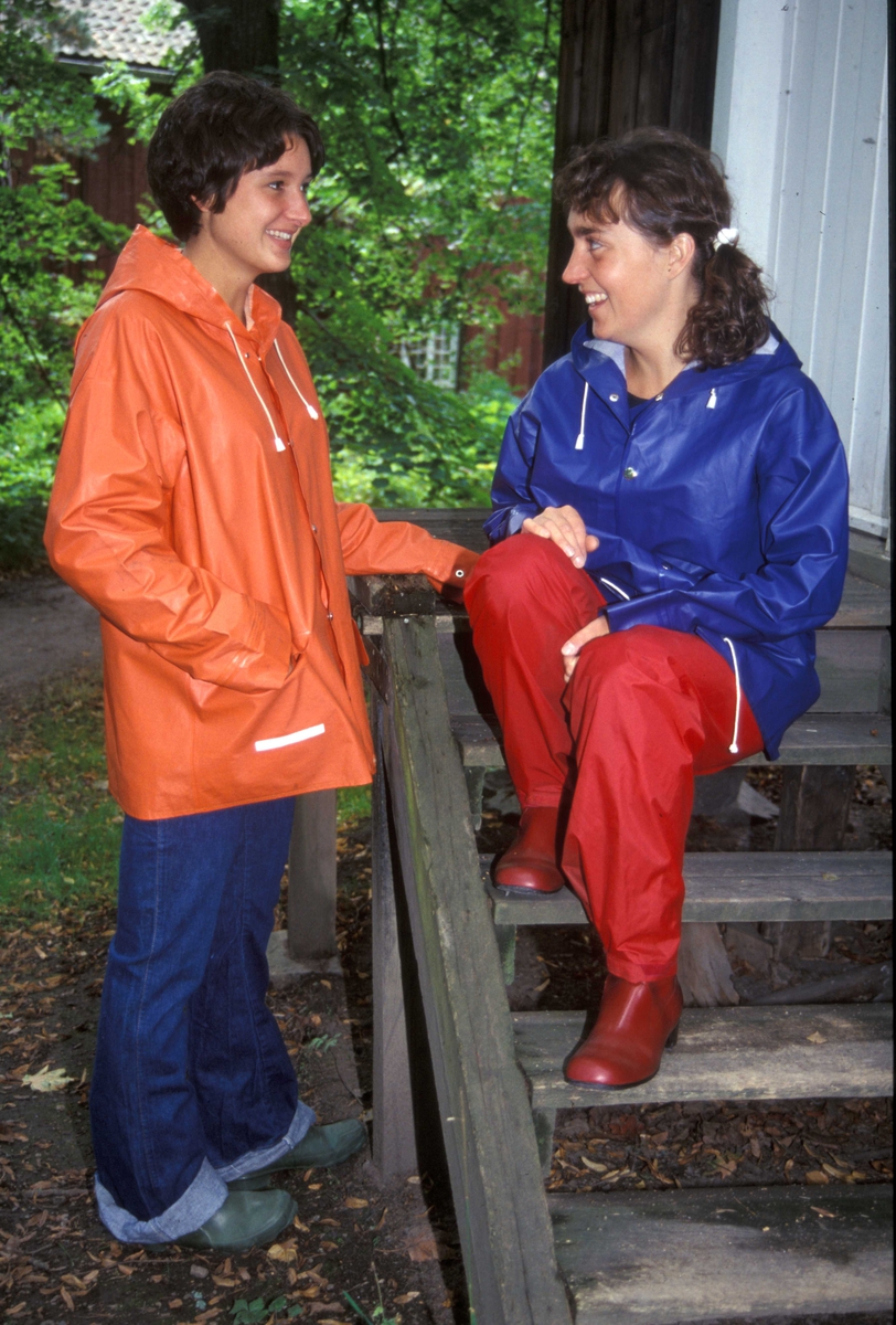 Regntøy, to kvinner i blå og orange seilerjakke ved trapp