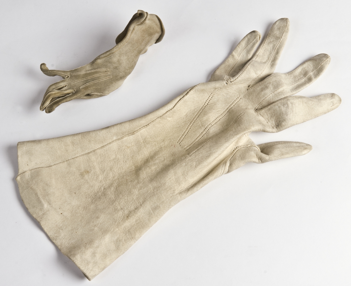 Et par hvite hansker i semsket skinn. Den ene er bltt vasket og er stiv og liten.