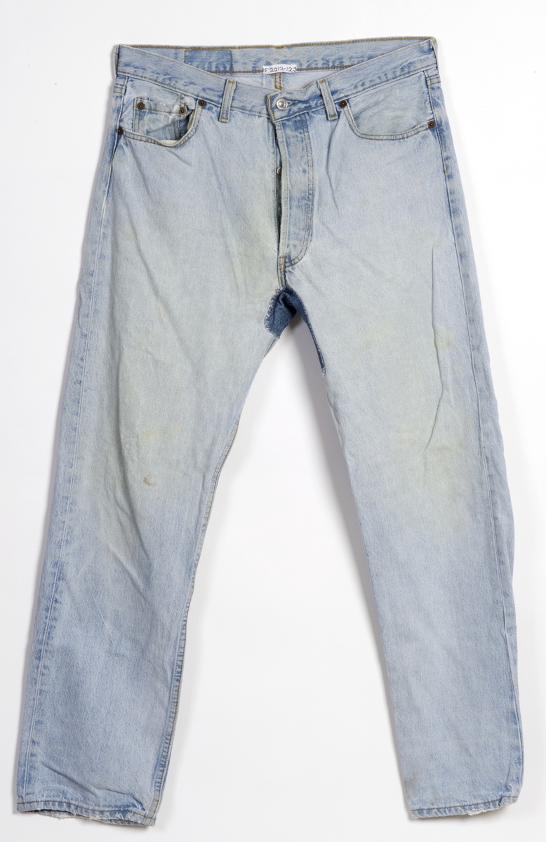 Jeansbukse i lyseblå, str. W 36 L 32. Utvasket lærlapp på høyre bakside. Reparasjon i skrittet av jeansstoff i en mørkere farge.