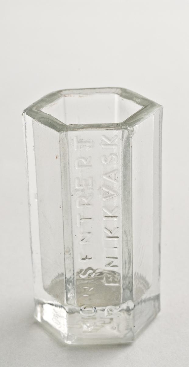 Måleglass i glass. 6-kantet, sylindrisk. Støpt i glasset mengdemålet 15 cm3 og 
10 cm3