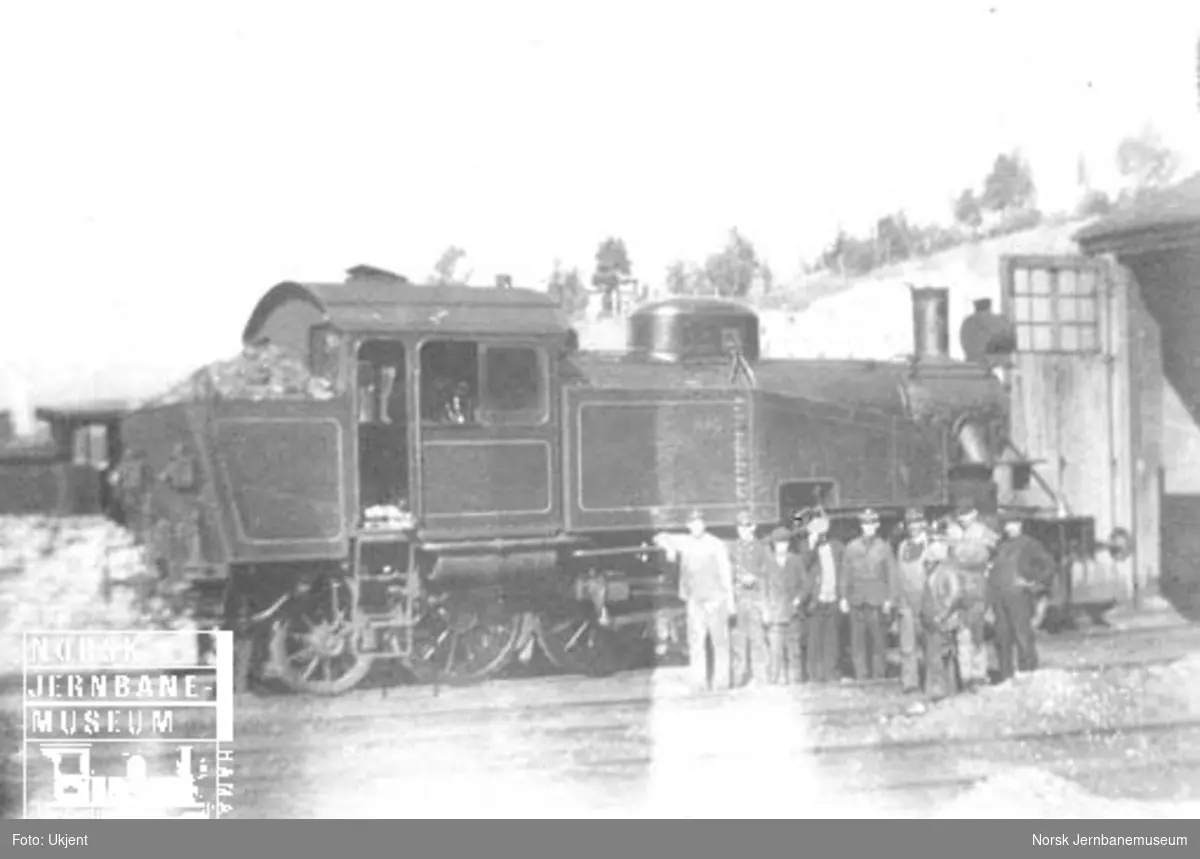 NSB damplokomotiv type 34a nr. 345 med oppstilte jernbanefolk utenfor lokomotivstallen på Dombås
