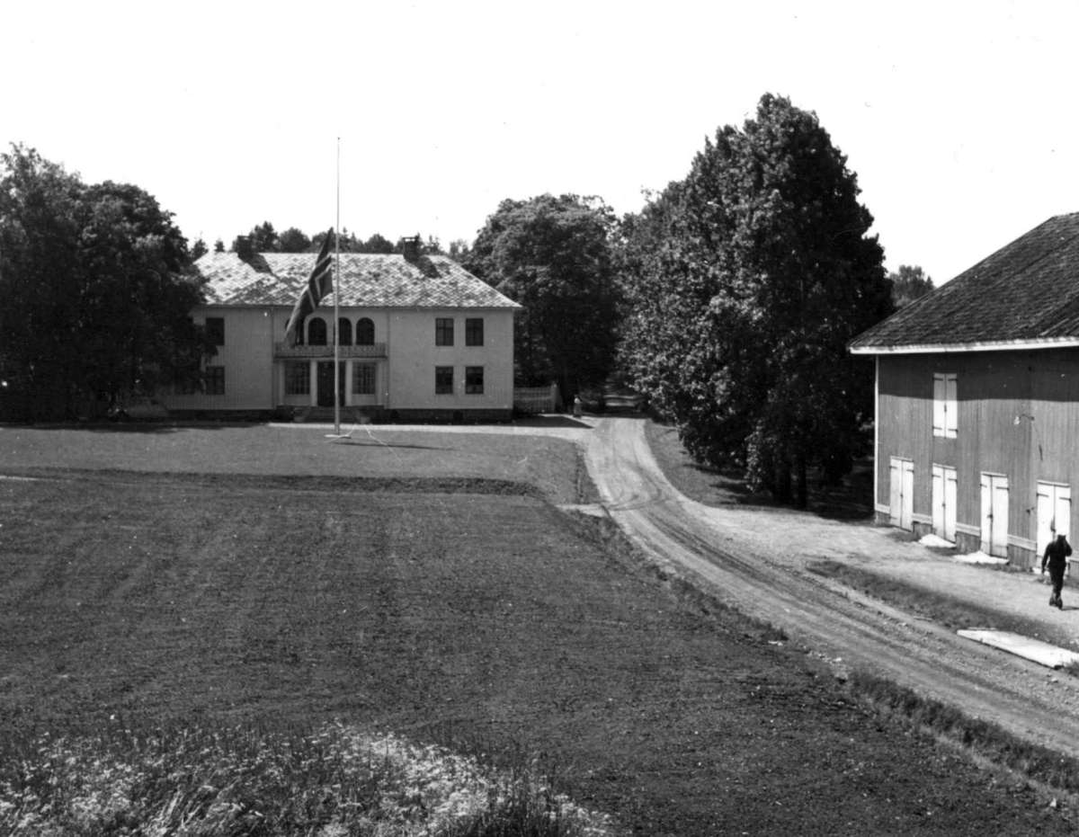 Haugrim, Aurskog, Akershus 1954. Hovedhuset med flagg på halv stang og uthus.
Fra dr. Eivind S. Engelstads storgårdsundersøkelser 1954.