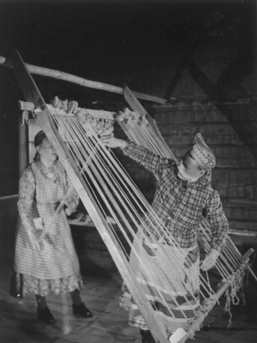 Greneveving (19). Skoltesamene Darja Jefreimov og Naska Moshnikov strammer rennningen til greneteppet. Seurasaari 1955.
