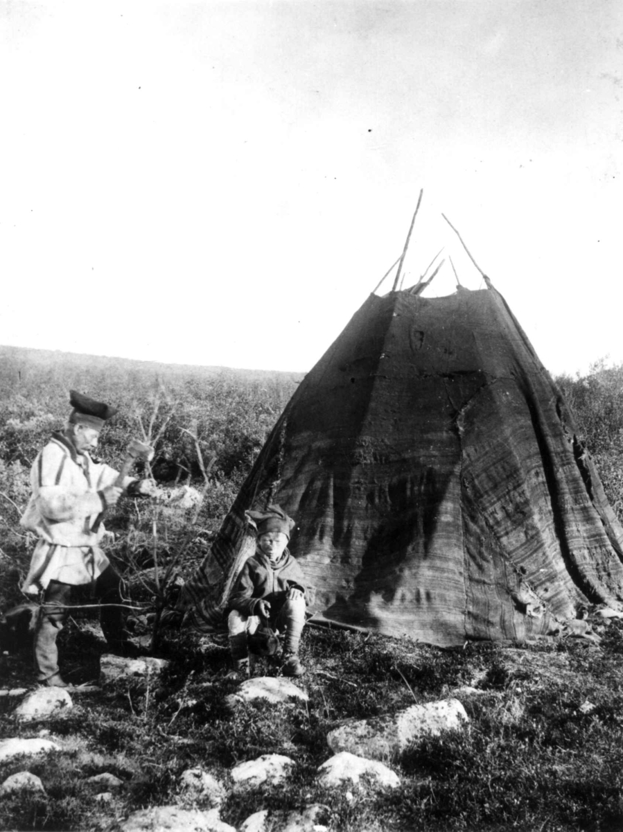 Enn gutt og en mann utenfor teltet mellom Bossekop og Karasjok 1897. Bildet sannsynligvis tatt i retning Joatkajavre. Personene er Karasjok-samer.