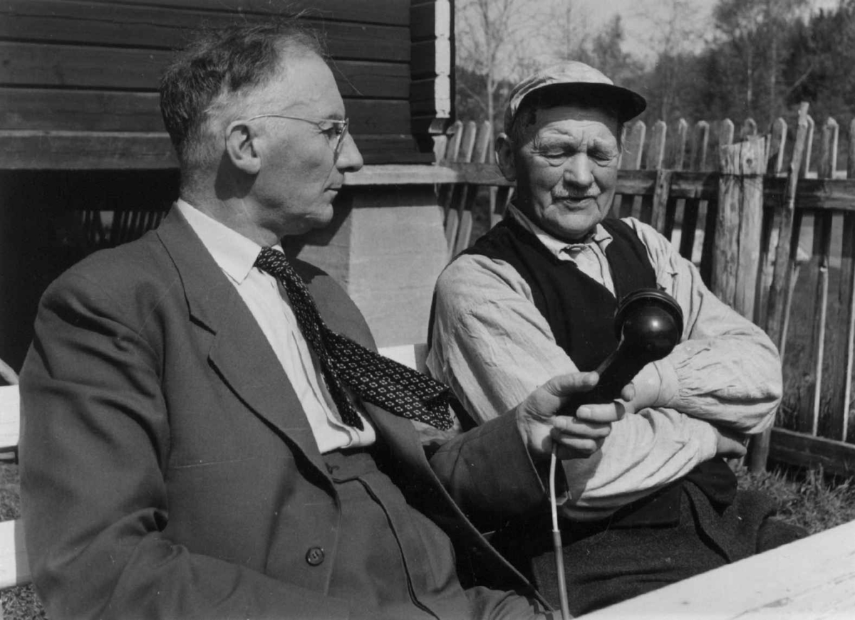 Professor Hilmar Stigum, førstekonservator på Norsk Folkemuseum, fotografert 16. mai 1960, under en tjenestereise. Han er her i samtale med Alfred Iversen på Ullbråtan.