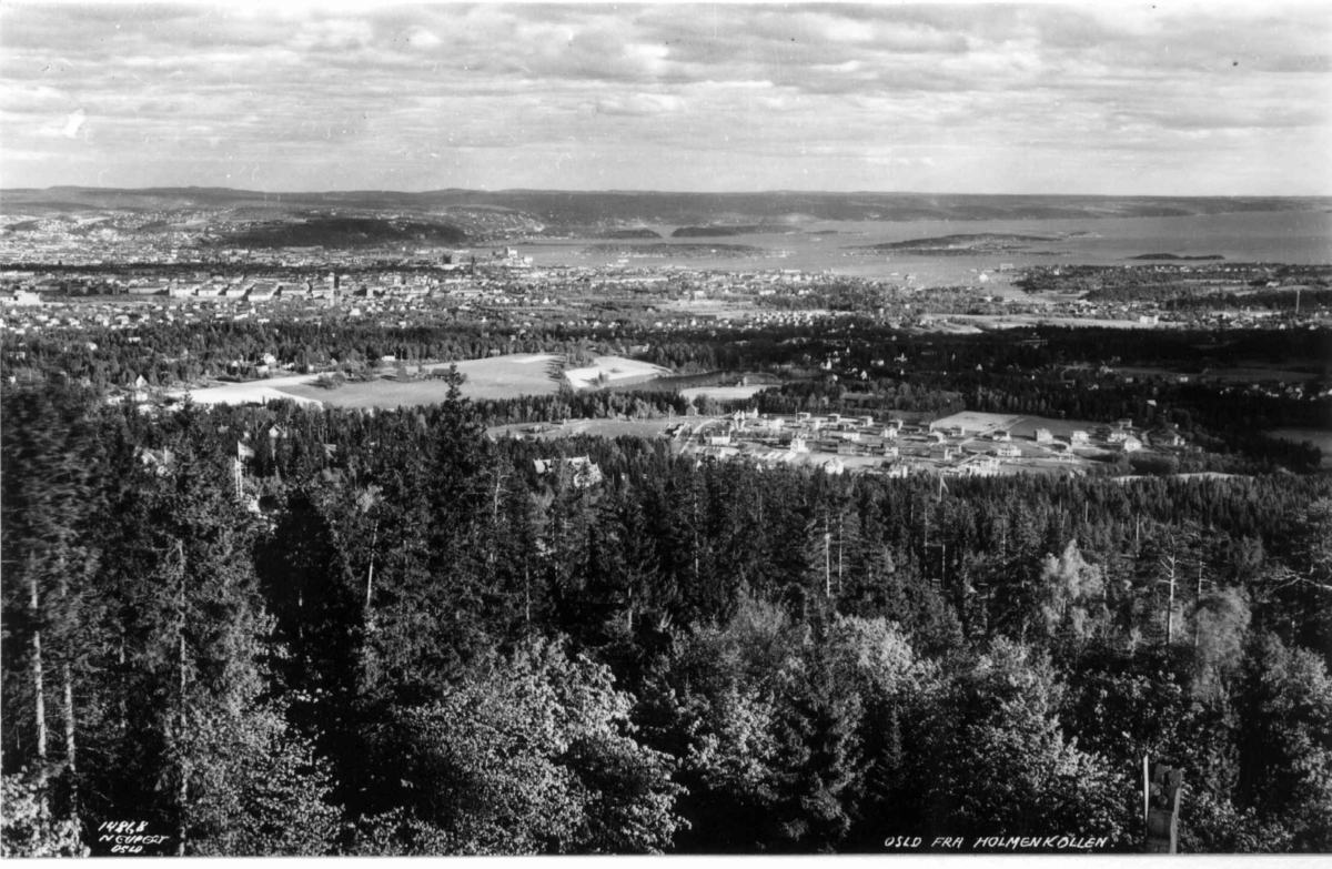 Utsikt fra Holmenkollen, Oslo 1936. Oversiktsbilde. Skog og villabebyggelse. I bakgrunnen sentrum og fjorden med øyene.