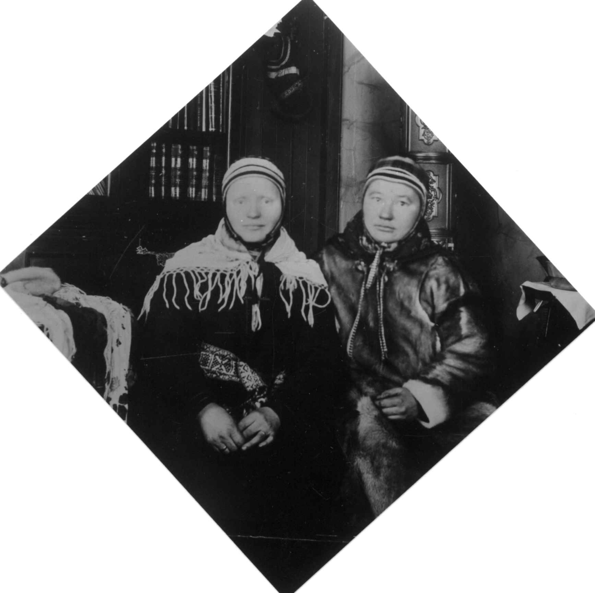 Portrett av 2 samiske piker fra Bøkfjorden, Sør-Varanger, Finnmark. De sitter i et interiør i doktorgården Solheim, Kirkenes, Sør-Varanger, Finnmark - ekteparet Wessels hjem.