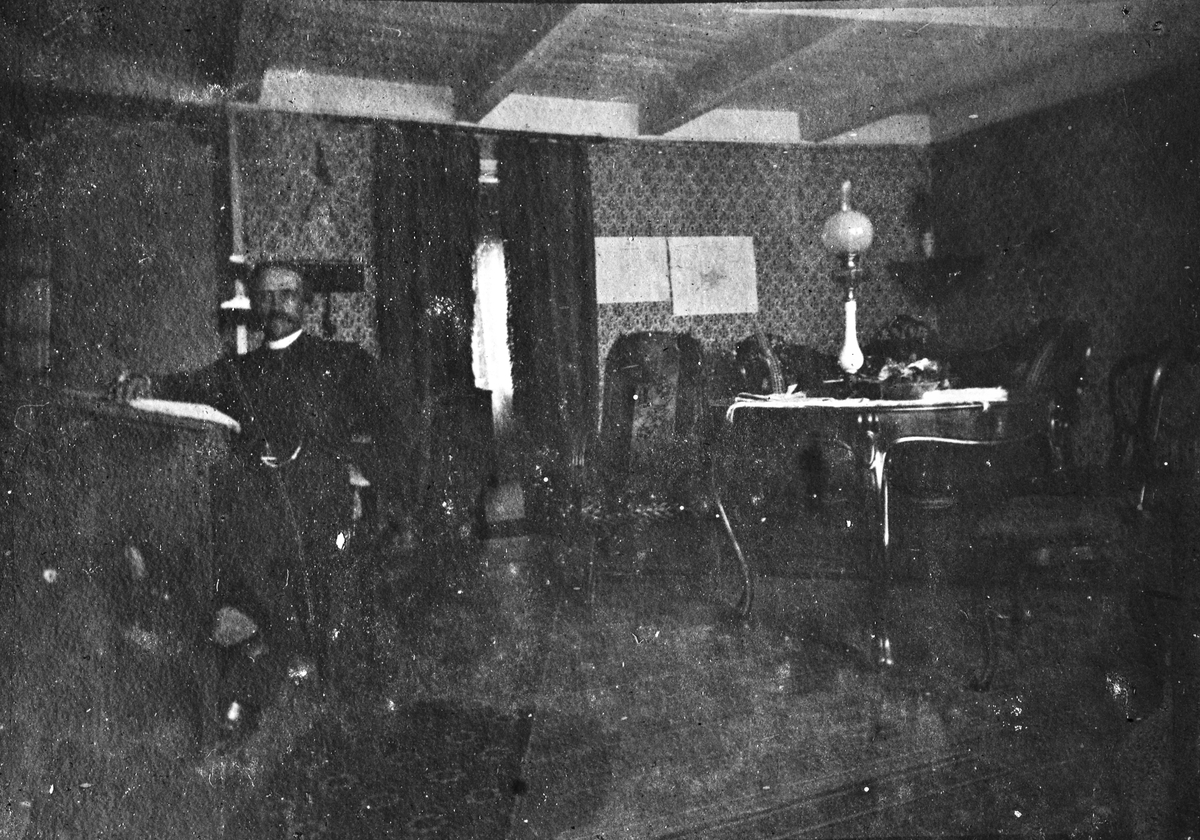 Interiør stue, sannsynlig prestegården i Fyresdal, Telemark, med prosten sjøl, Jon Lauritz Qvisling (1844-1930) sittende mot venstre. Se også NF.13246-098.