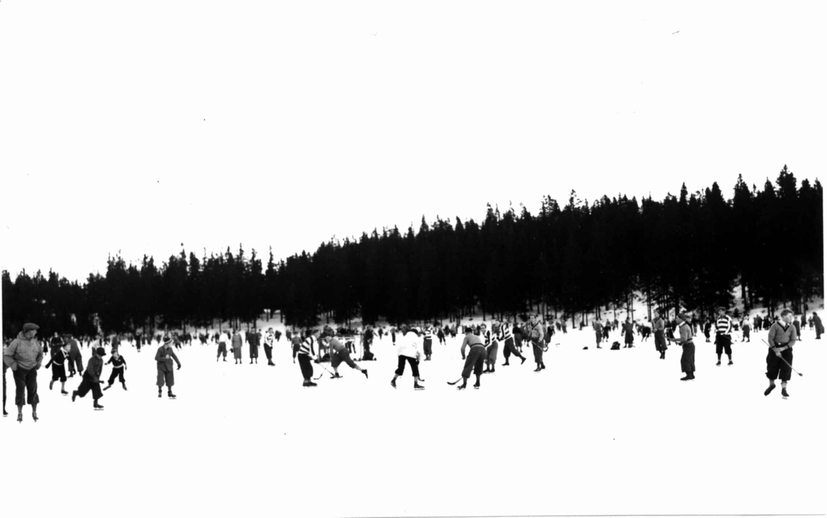 Tryvann skøybane, Oslo. 1934. Skøyteløpere i sving på isen. Noen med bandykøller.