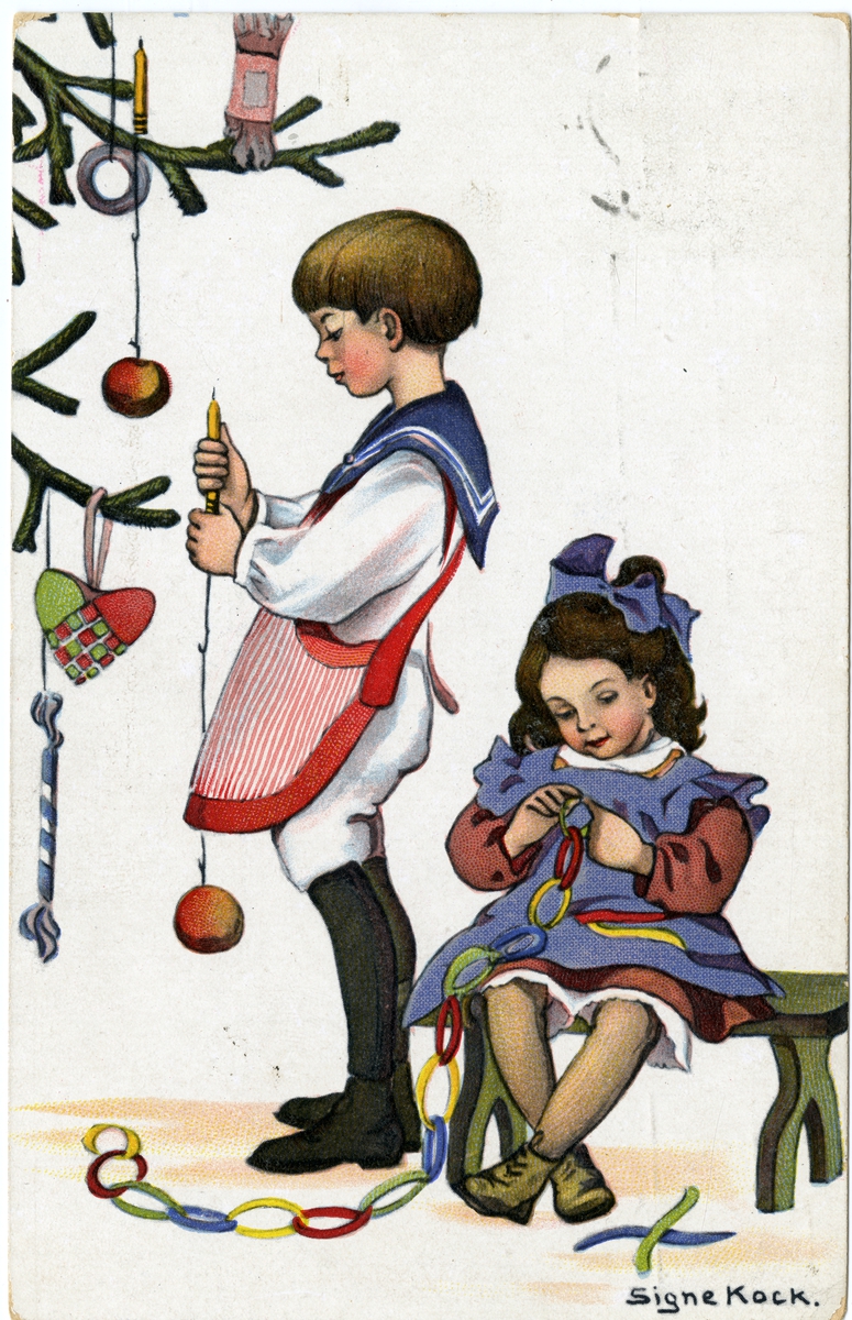 Julekort. Jule- og nyttårshilsen. To barn lager julepynt og pynter juletre. Gutten er kledd i matrosdress. Illustrert av Signe Kock. Poststemplet 23.12.1918.