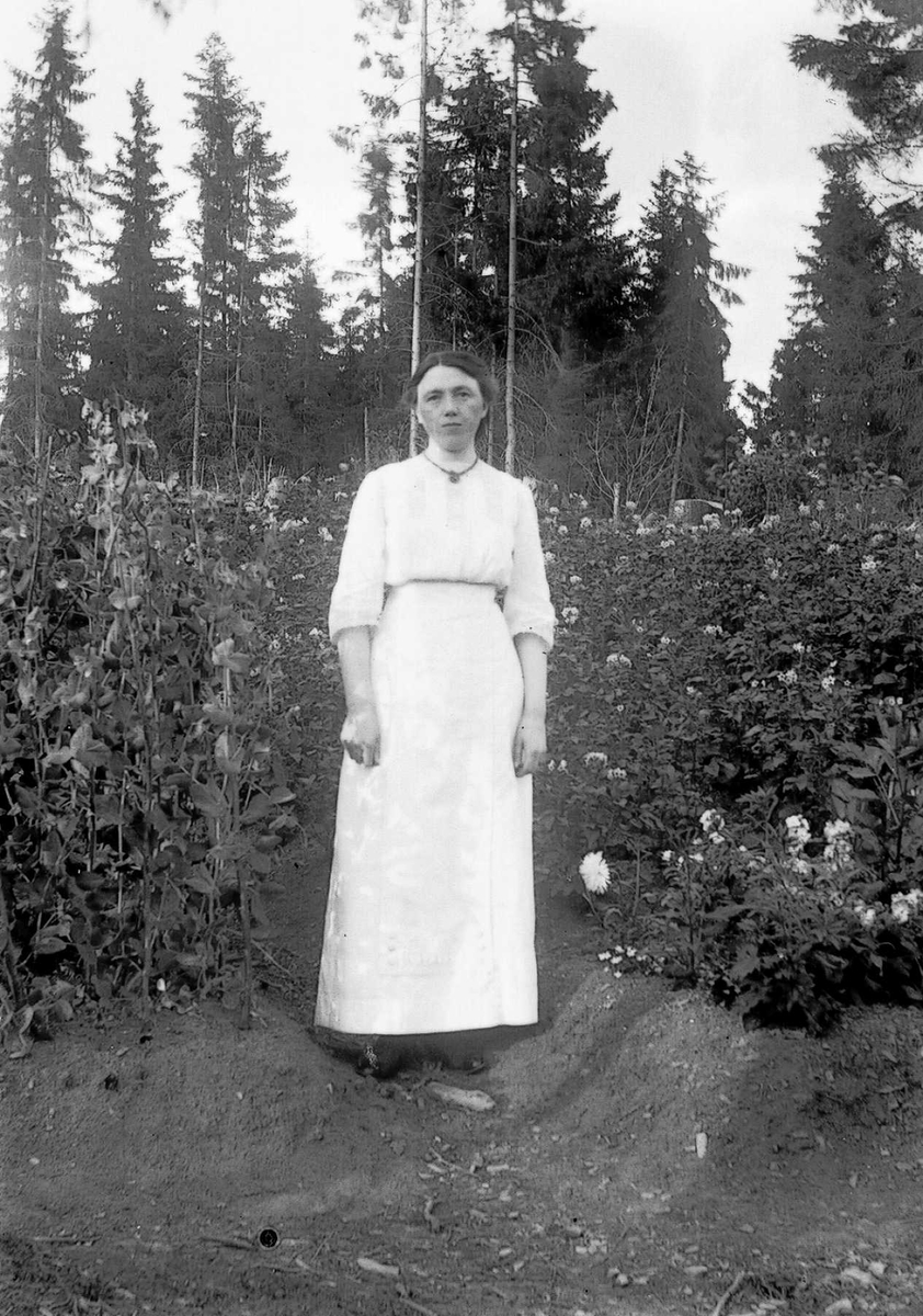 Kvinne i lang hvit kjole på tomta i Ringstabekkveien.