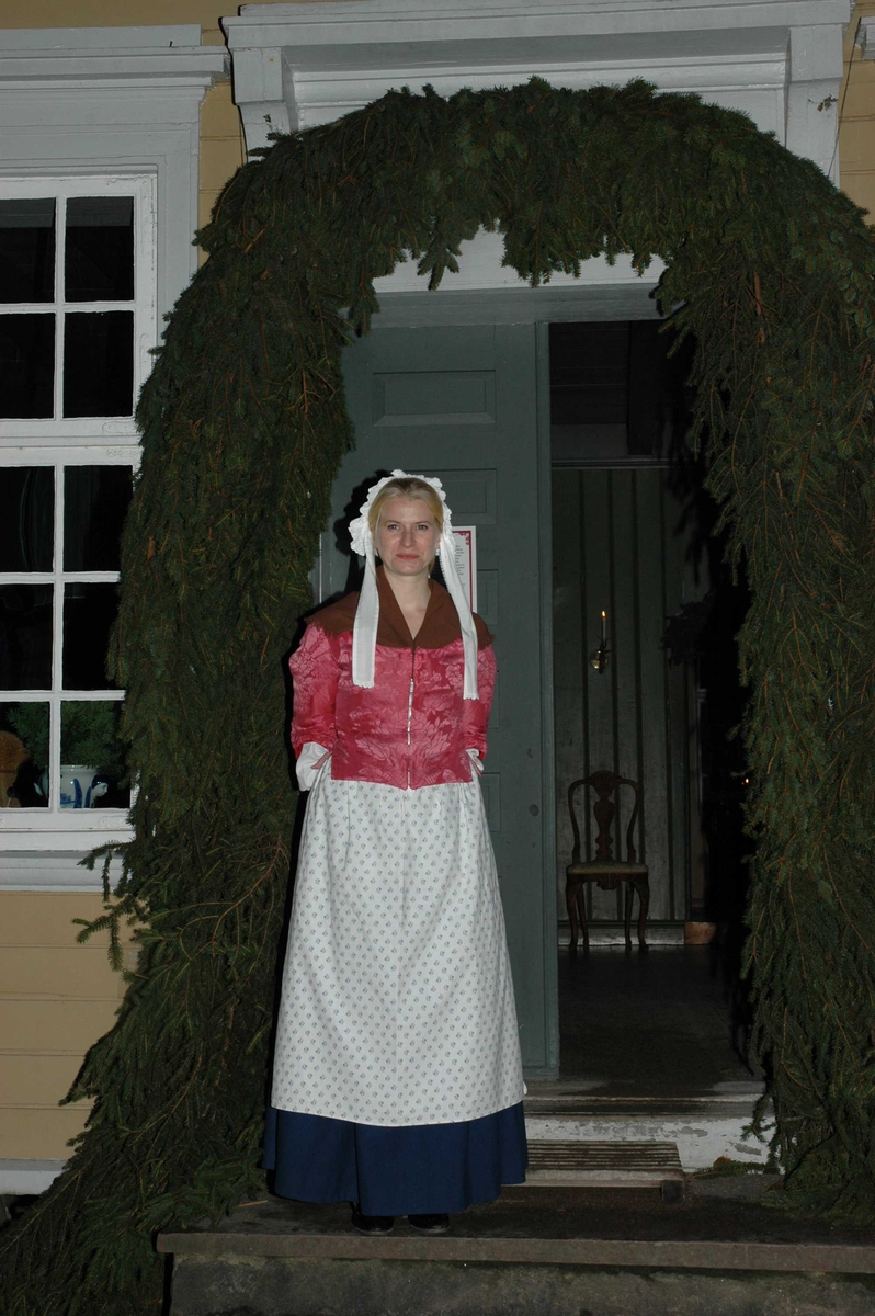 Julemarked 27.11.2005. Heidi Uleberg i tidsriktig kostyme i døråpningen i Chrystiegården, bygning nummer 227 i gamlebyen på Norsk Folkemuseum. Rundt døren er det pyntet med granbar.