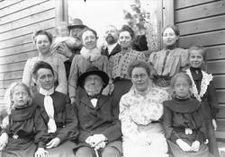 Familieportrett, stor gruppe mennesker foran bygning.
Famil