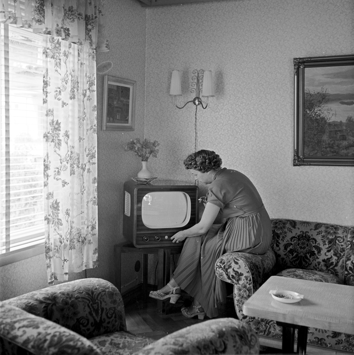 Ny tid for radio og fjernsyn, apparatet er plassert i stuen,kvinne prøver om det virker, 22. juli 1954.