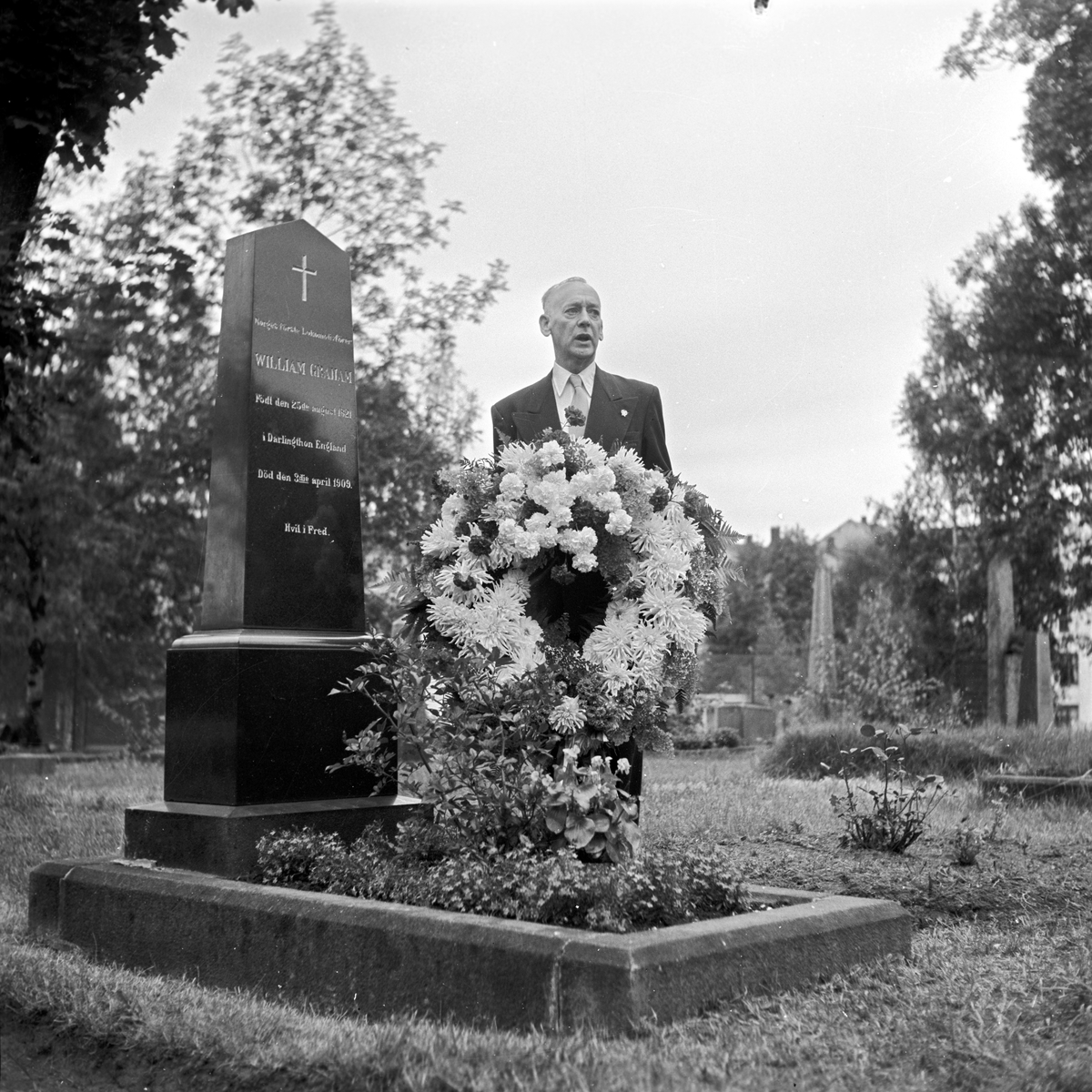 Serie. William John Graham, Rolf Wilhelm Graham og Jonny Graham legger ned krans på William Grahams gravplass. Fotografert 1. sept. 1954.