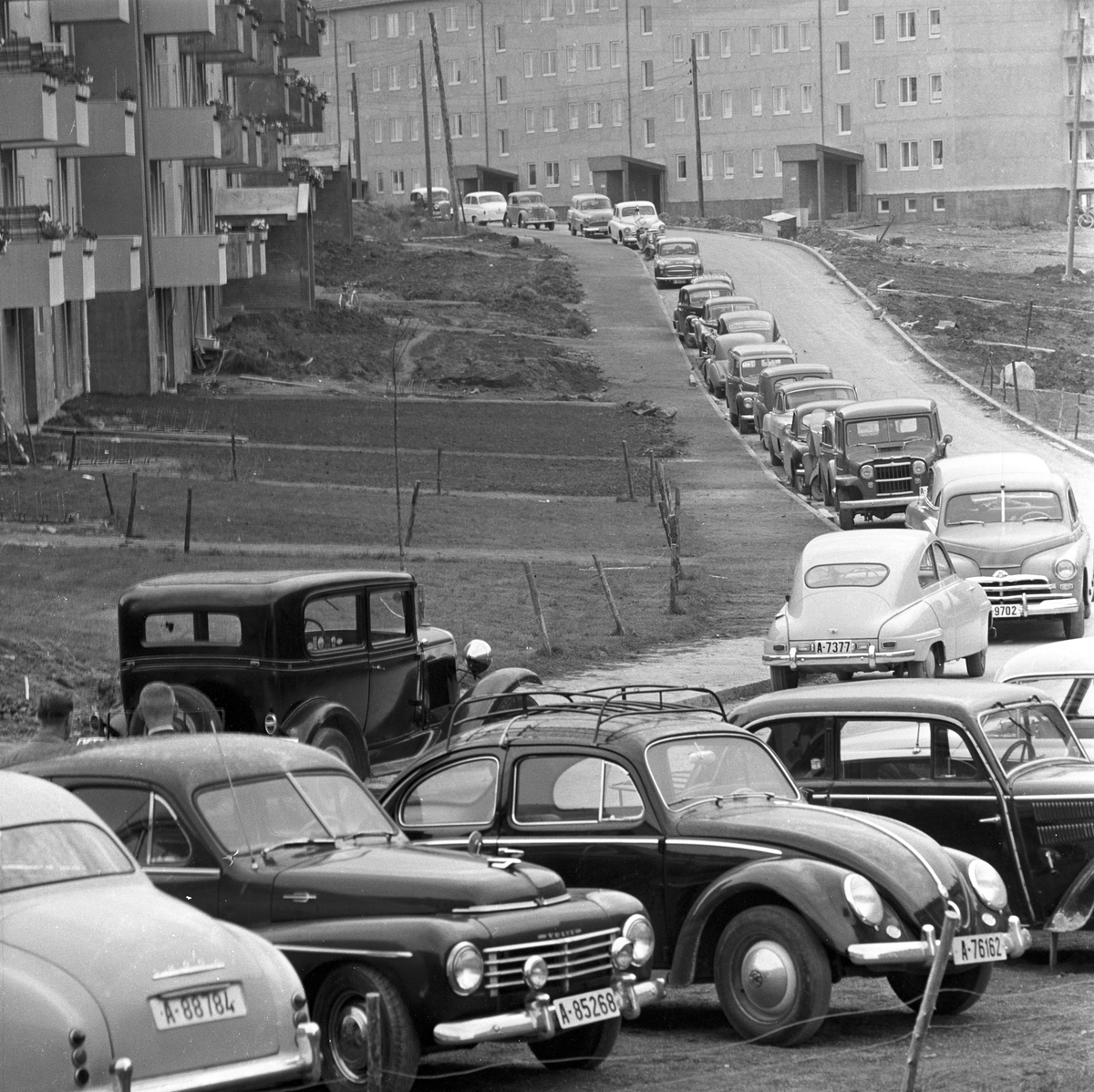 Serie. Parkeringsvansker i de nye boligområdene i Oslo, Manglerud og Lambertseter. Trehjulsykkelen må parkeres på gresset. Manglerud, Rugveien. Fotografert august 1958.