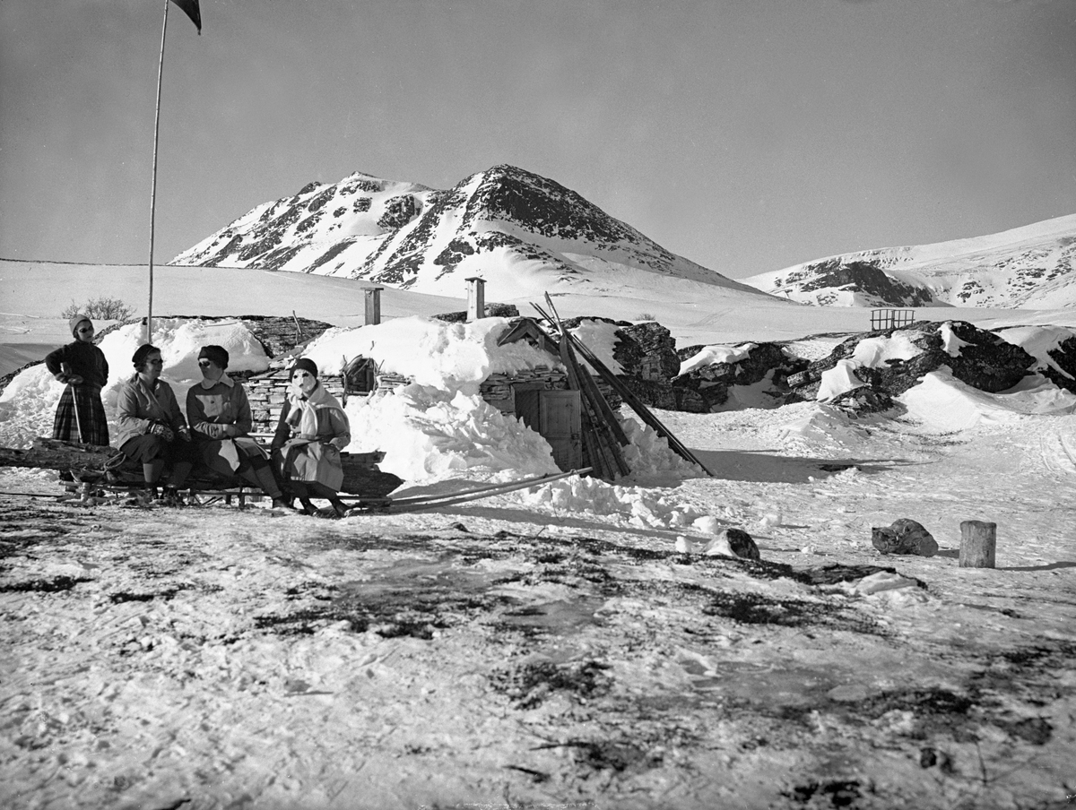Noen damer sitter foran Peer Gynt hytta i påsken, Rondane. Fotografert 1932.