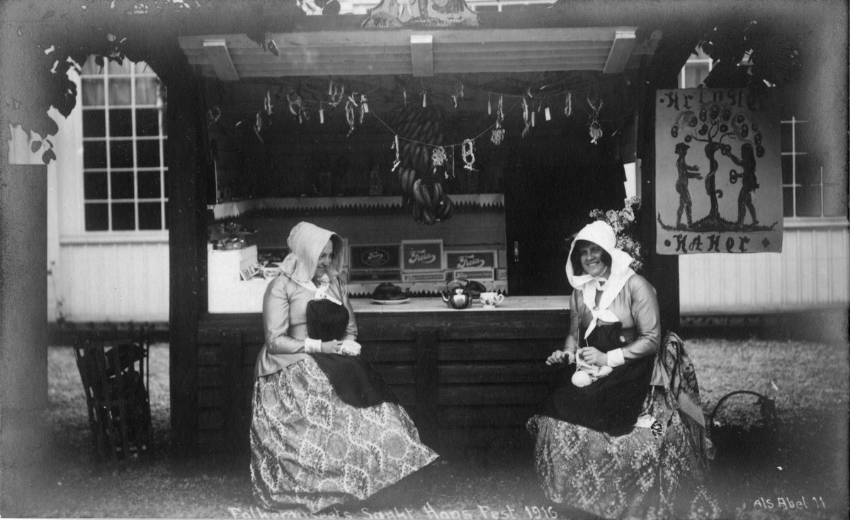 Postkort. Kvinner foran markedsbod med salg av kringler, kaker og sjokolade. Norsk Folkemuseums St. Hansfest 1916.