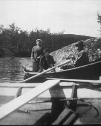 Avfotografering. Menn og en kvinne i en robåt.