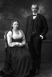 Gruppeportrett, mann og kvinne. Hun i beltestakk med bolesøl