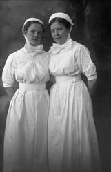 Gruppeportrett, to piker i sykepleieruniform.