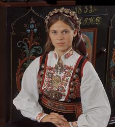 Brudekledd kvinne med malerull. Bø i Telemark.