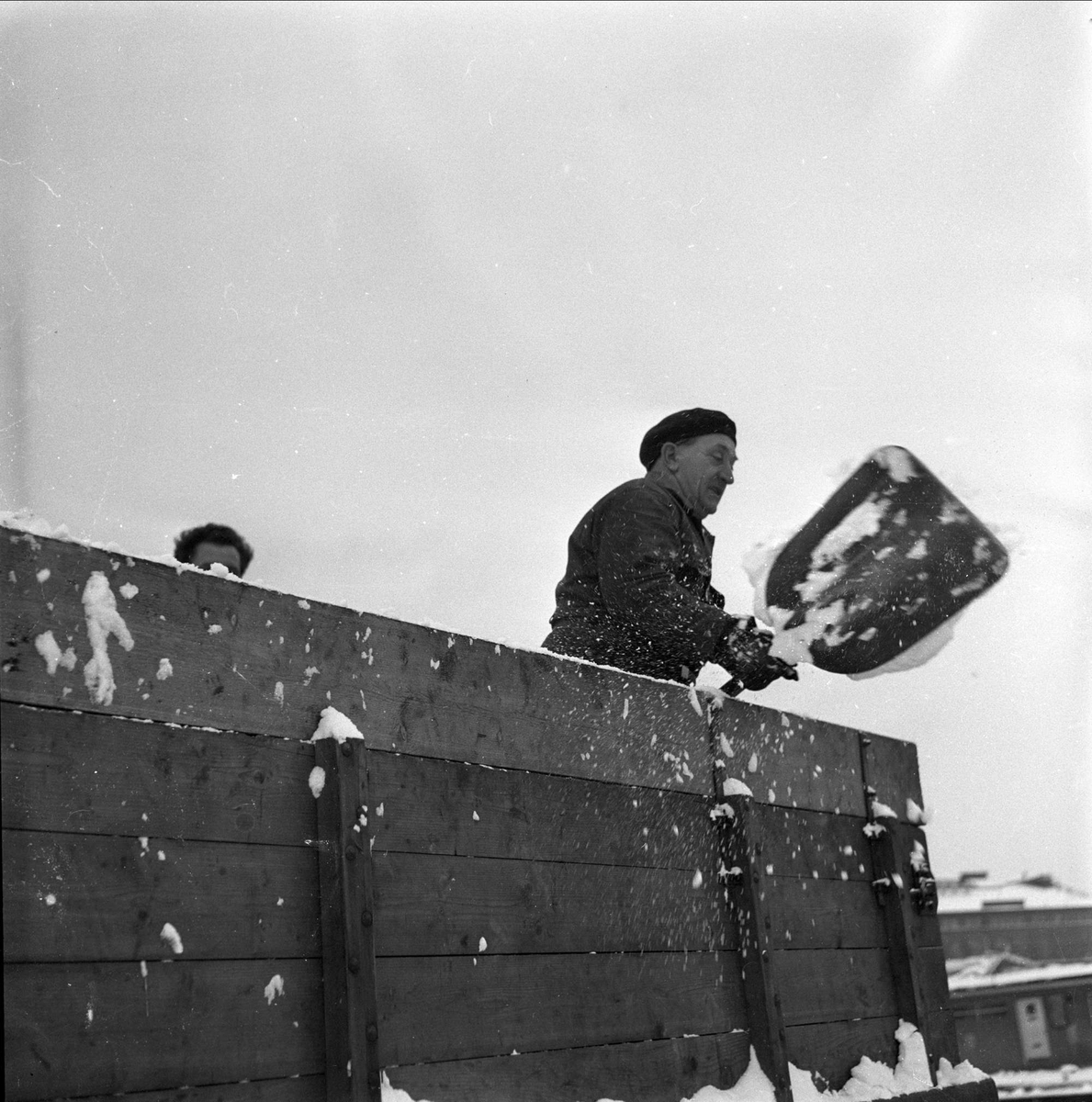 Mann med spade med snø på lastebil, Oslo, 28.11.1956.