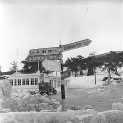 Dombås, Dovre, 21.03.1959. Veiskilt, kafeteria og bil.