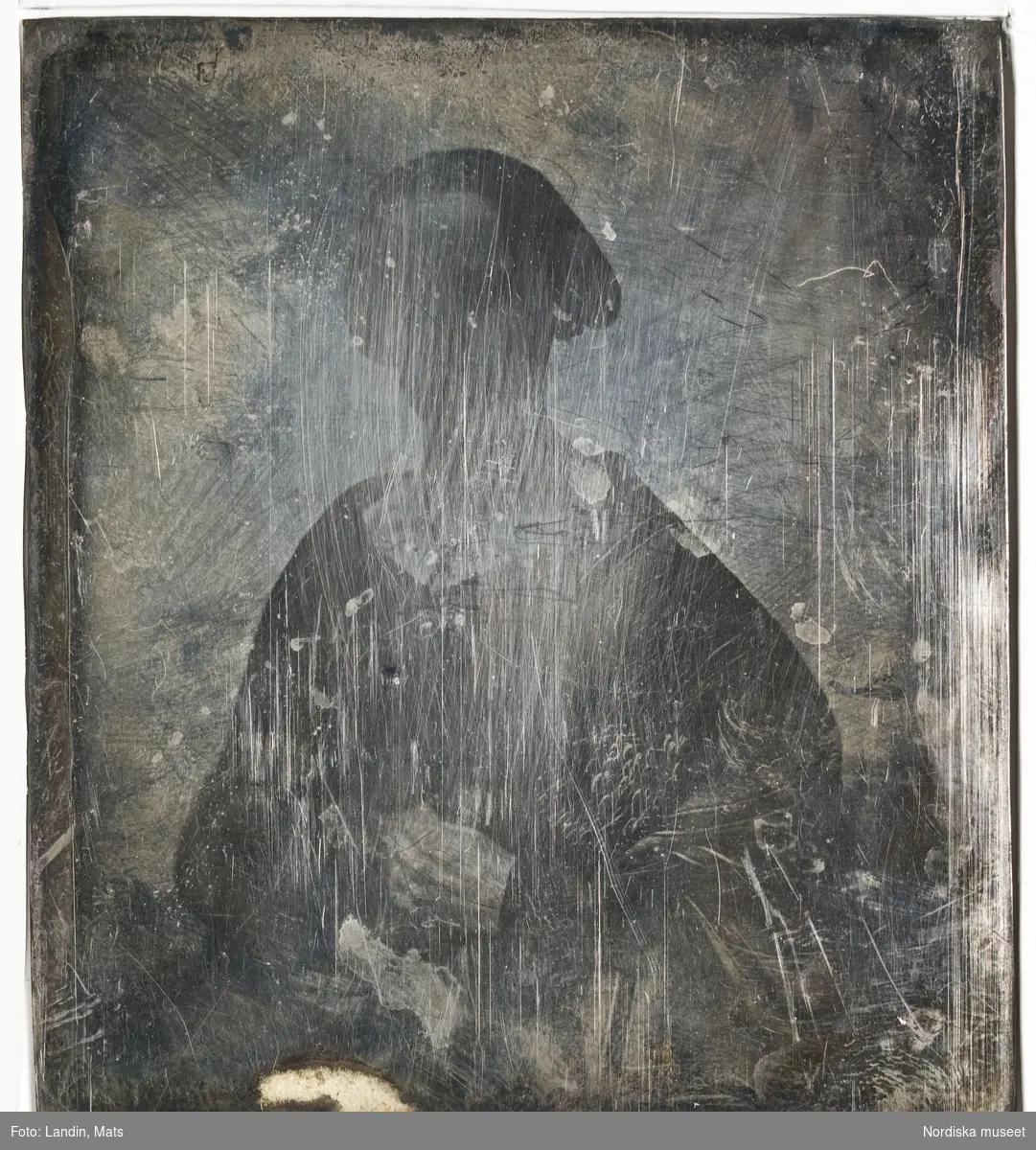 Porträtt av okänd kvinna. Dagerrotyp / daguerreotyp, ca 1850, svårt repad/oxiderad. Nordiska museet inv.nr 205461b + c (fodral).
-
Portrait of an unidentified woman. Effaced sixth-plate daguerreotype, c. 1850.
