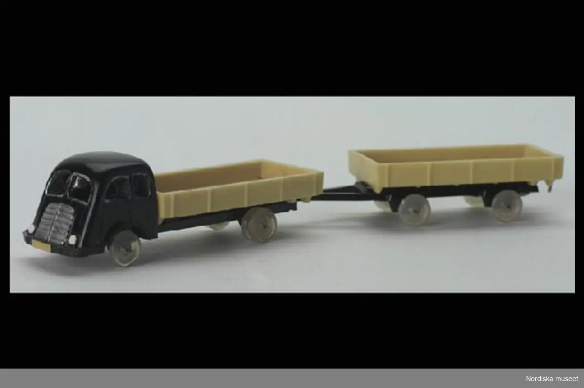 Inventering Sesam 1996-1999:
Lastbil och släp
L = 14,5 cm
B = 2,5 cm
H = 2,5 cm
Lastbil med släp i plast. Lastbil; svart förarhytt och gult flak, släp; gult flak och svart dragögla. Båda bil och släp har transparenta hjul. Undertill märkta med två W, ett rättvänt och ett upp och ner. 
Inköpt för 2,10 kr 1951 på postoder från Tyskland.
Givaren samlare av leksaksbilar 1947-1952, se inv 263.905 - 264.120.
Bilaga
Leif Wallin 1996