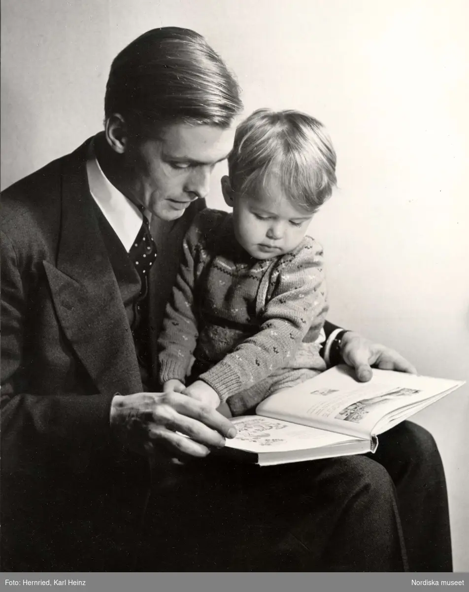 Man med ett barn i sitt knä läser ur en sagobok.