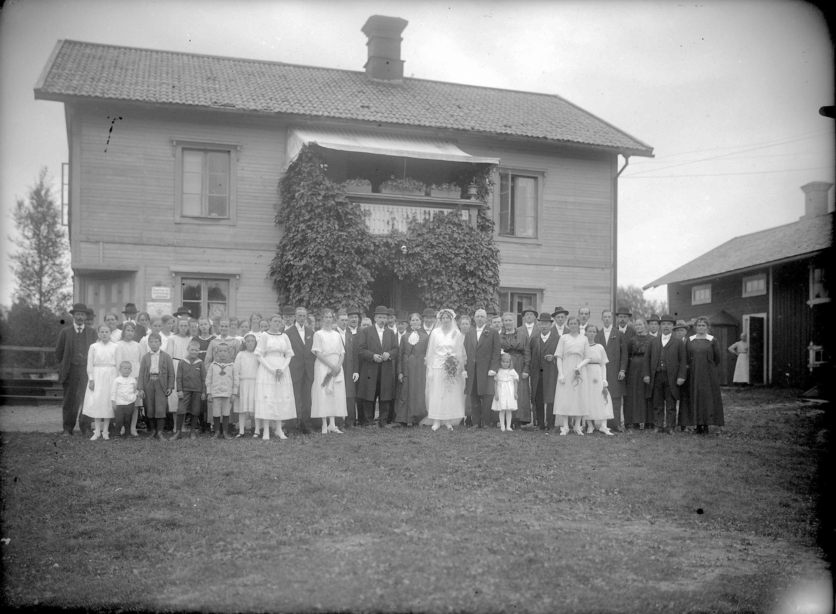 Gruppfoto framför Erik Renströms hus med brudparet i mitten, från början av 1900-talet. Lima, Dalarna