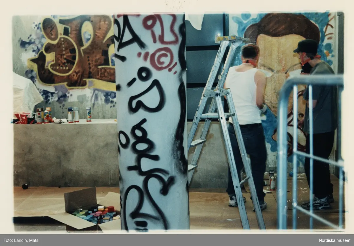 Nordiska museet utställning "Staden - himmel eller helvete"  i samband med Kulturhuvudstadsåret 1998. Graffitimålare spraymålar väggfält i museets lokaler inför utställningen.