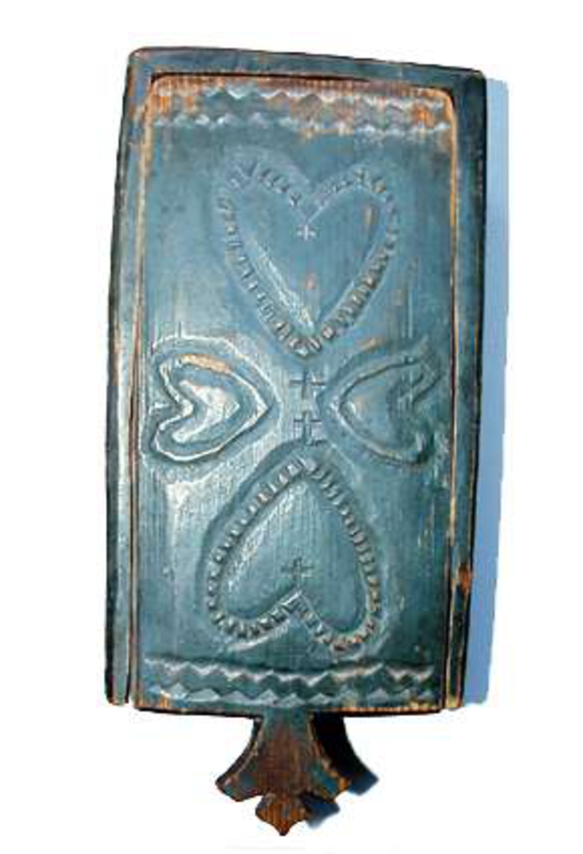 Låda av trä, skuren i ett stycke med skjutlock. Helt målad i grönblått. Skuren dekor på locket med fyra hjärtan, kors och sicksackband. På sidorna sicksackband och nagelsnitt.