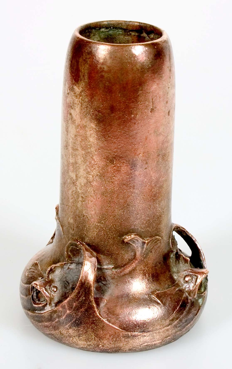 Två vaser av brons. Den mindre vasen är stämplad med Hugo Elmqvists gjutarstämpel, D.6, E Kock, A otydlig text= A.B. Elmqvistska gjutmetoden. Den större vasen är av grönpatinerad brons i jugendstil med fiskar simmande i vågtoppar i relief och på skulptur runt den vulstformade nederdelen. Signerad E H. På undersidan rund gjuten stämpel och E XII.