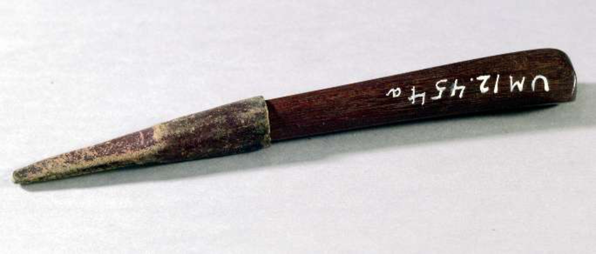 Fickkniv med kort trekantigt blad av stål stämplat: V. S. Åttkantigt skaft av brunbetsad ek. Slida av rödbrunt läder.