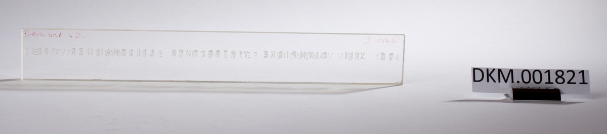 En rektangulær skive med inngravert tekst som er lik på begge sider av skiven.