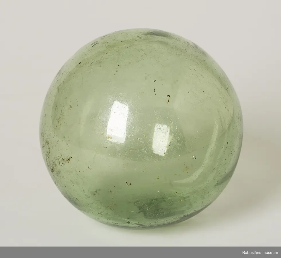 Ljusgrön kula. I glasmassan i proppen som satts i puntelhålet efter
blåsningen är en treklöver inpressad i relief.