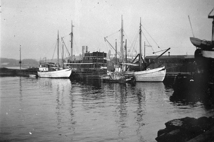 Enl. tidigare noteringar: "Harry Ödmans fraktjakt "Thea", båten till höger, vid lotsverkets brygga vid Kusten Göteborg. I bakgrunden ett av Lotsverkets fartyg. Längst till höger syns aktern på en Lysekilsbåt som ligger på slipen. Jakten "Thea", 49 fot, lastar ca 70 ton, byggd 1911 i Skien Norge, som fiskebåt. H. Ödman köpte den 1933 av Bergs varv Hälsö och ändrade den till fraktjakt. Sålde den 1940, på grund av oljebristen under kriget. Jakten användes därefter bl.a. att frakta fiskfångsten med från Fotö till fiskhamnen i Göteborg. Repro 1985 av foto tillhörande Harry Ödman, Dragsmark".